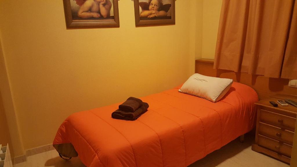 ein kleines Schlafzimmer mit einem Bett mit einer orangefarbenen Decke in der Unterkunft Hotel Banyeres in Banyeres de Mariola