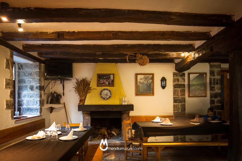 comedor con 2 mesas y chimenea en Casa Rural Eleizondo Haundia, en Itziar