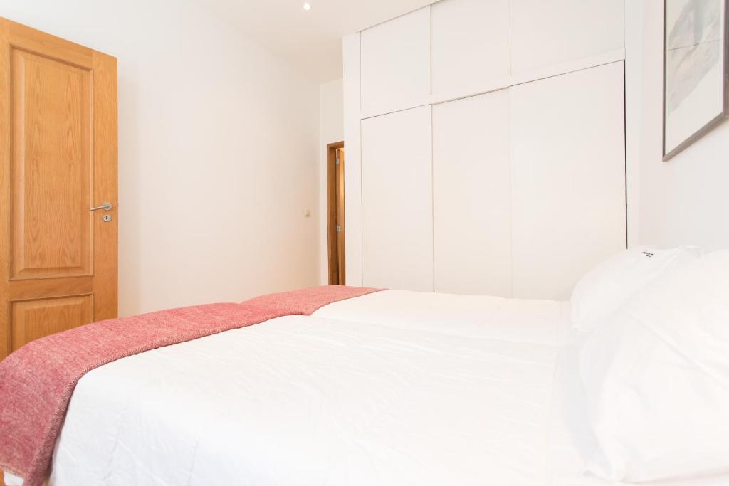um quarto com uma cama branca e uma porta de madeira em FLH Castelo Cozy Flat em Lisboa