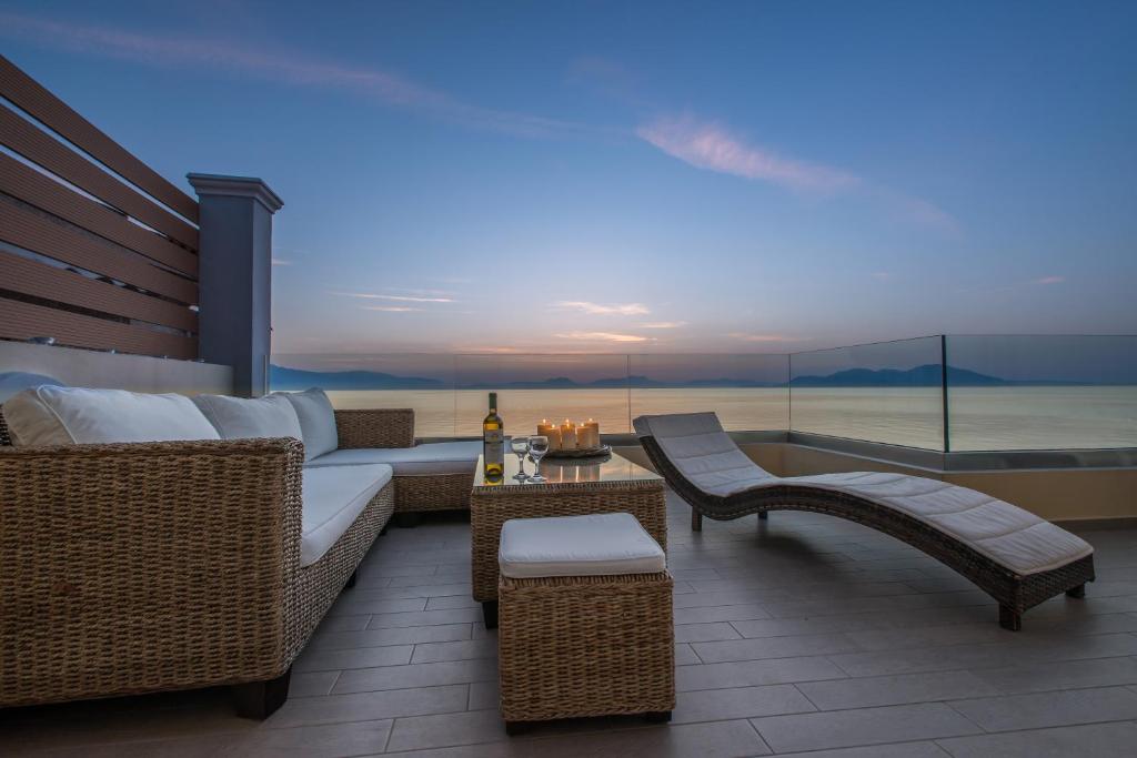 a patio with wicker furniture and a view of the ocean at Diamante Beachfront Suites in Xylokastron