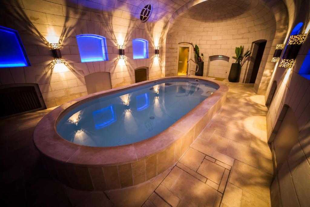 モンバゾンンにあるシャトー ダルティニーの青い照明付きの客室内の大きなバスタブ