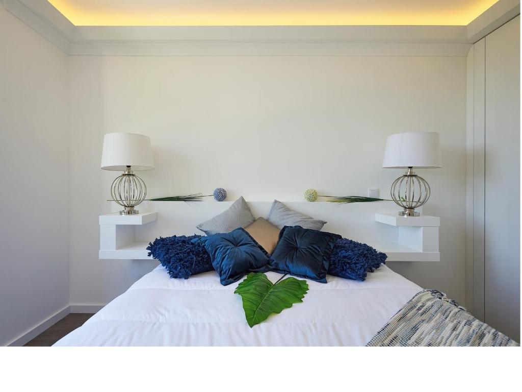 un letto bianco con cuscini blu e 2 lampade; di Sintra Design Apartment a Sintra