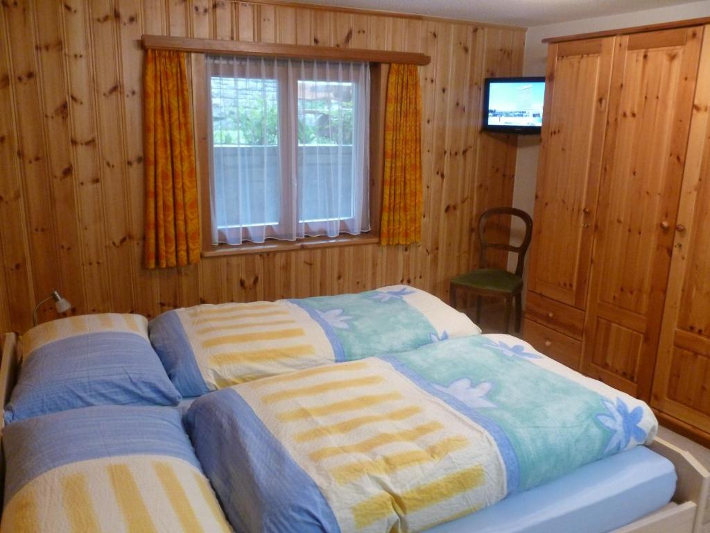 a bedroom with two beds in front of a television at Chalet Medi in Zermatt