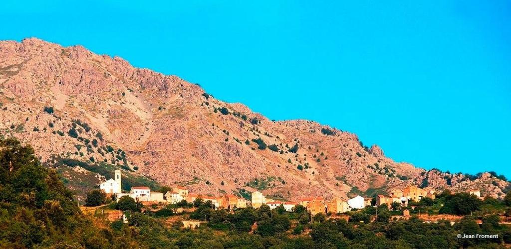 une colline avec un village en face d'une montagne dans l'établissement Auberge Casa Mathea, à Poggio-di-Venaco