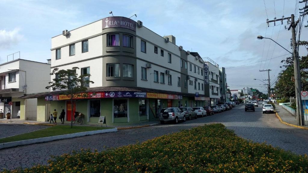 a white building on a street with parked cars at Iria's Hotel in Timbó