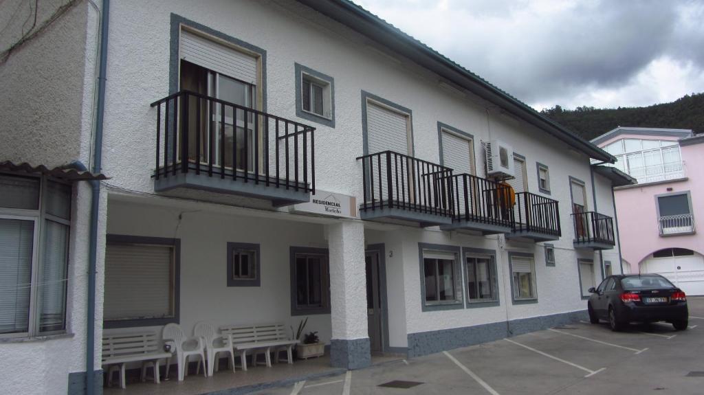 a building with tables and chairs in a parking lot at Residencial Martinho in Lousã