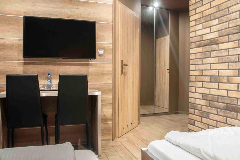 ein Hotelzimmer mit einem Tisch und einem Flachbild-TV in der Unterkunft Motel Podmiejski in Pleszew