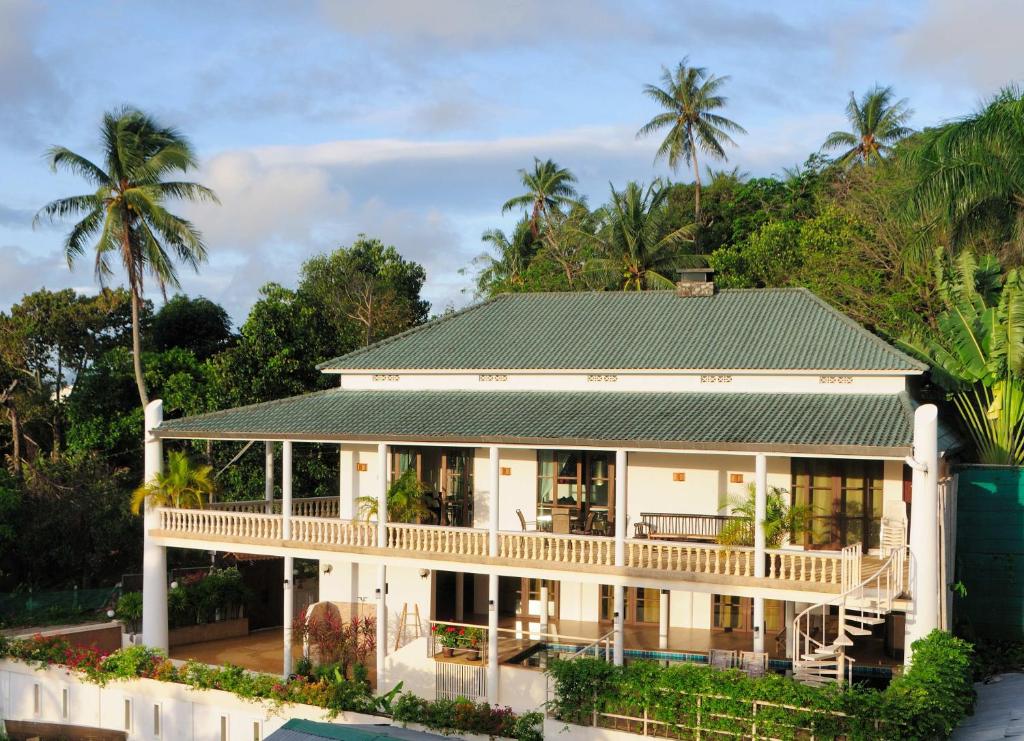 een groot wit huis met een groen dak bij Surin villa in Surin Beach