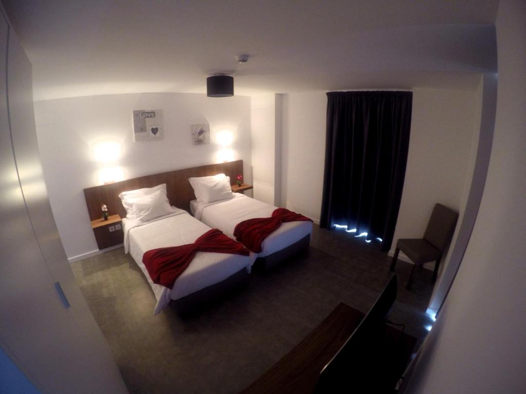 um quarto de hotel com duas camas e uma janela em Albergaria O Professor em Santa Cruz - Madeira