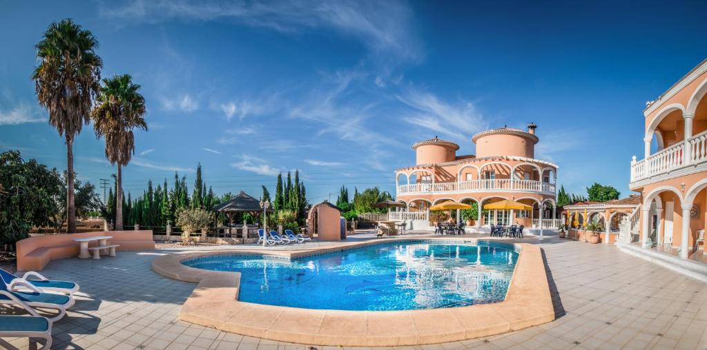 a resort with a swimming pool in front of a building at Pensión Los Caballos in Els Poblets