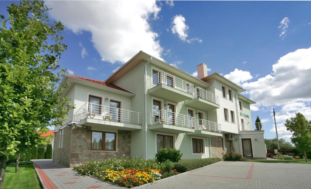 biały dom z balkonami i kwiatami na ulicy w obiekcie Jade Hotel-Ezüsthíd Hotel w mieście Veszprém