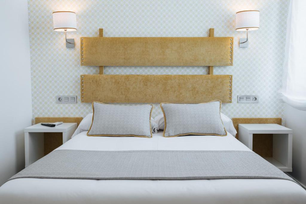 Un dormitorio con una gran cama blanca con dos mesitas de noche. en Hotel Santa Cruz, en Cangas de Onís