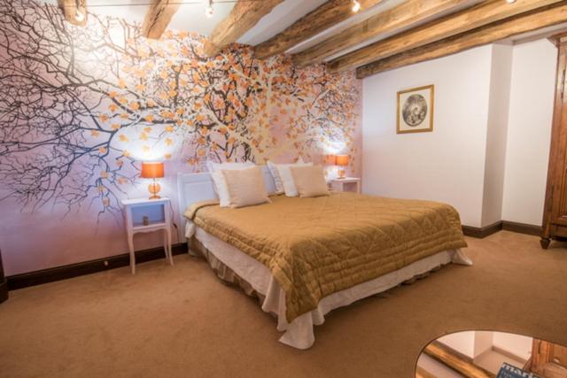 a bedroom with a bed with a tree mural on the wall at Hostellerie La Montagne in Colombey-les-deux-Églises