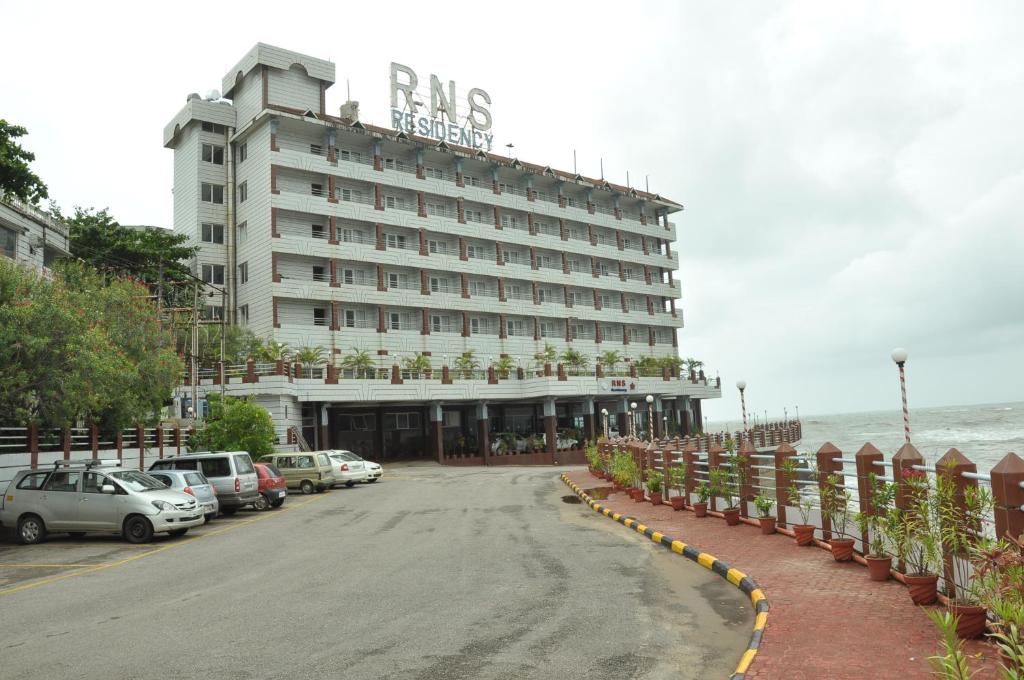 a large building with cars parked in front of it at RNS Residency Sea View in Māvalli