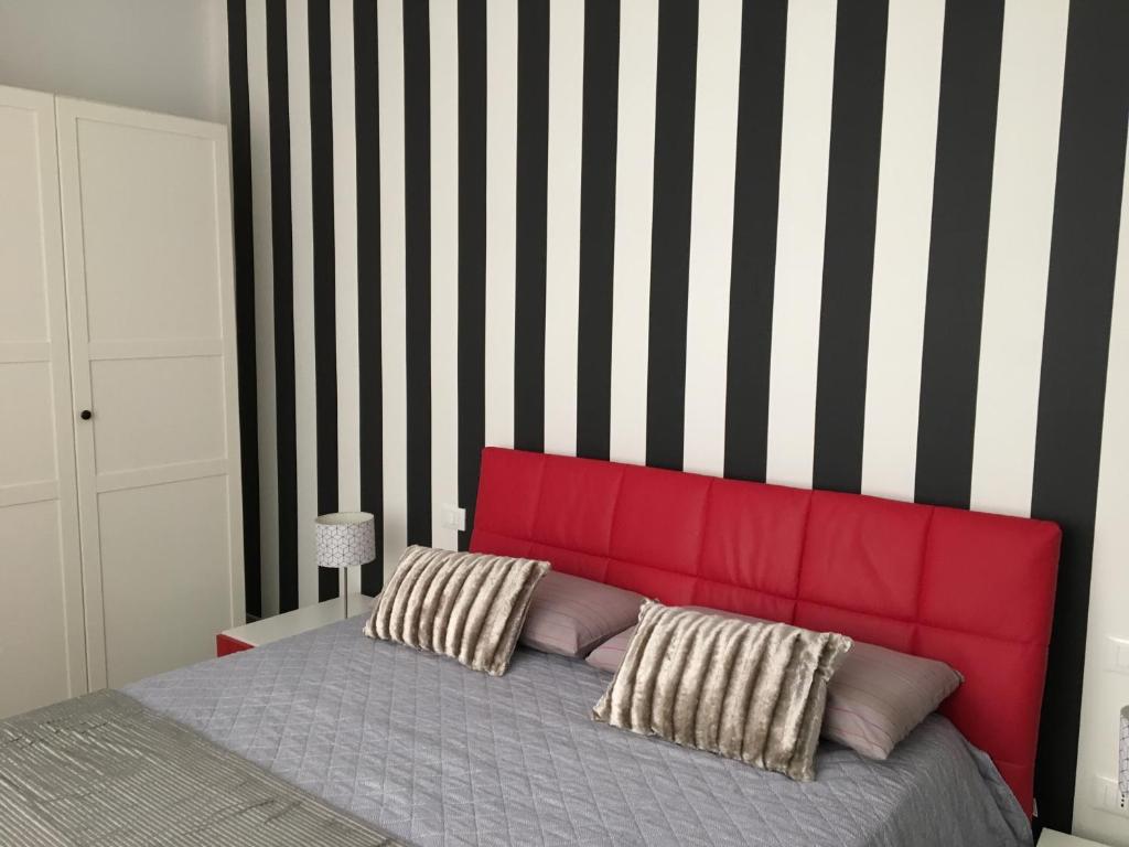 a bedroom with a red headboard and a striped wall at Casa Meri in Montesilvano