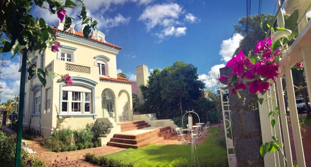 a large white house with purple flowers in the yard at Alquimista Montevideo in Montevideo