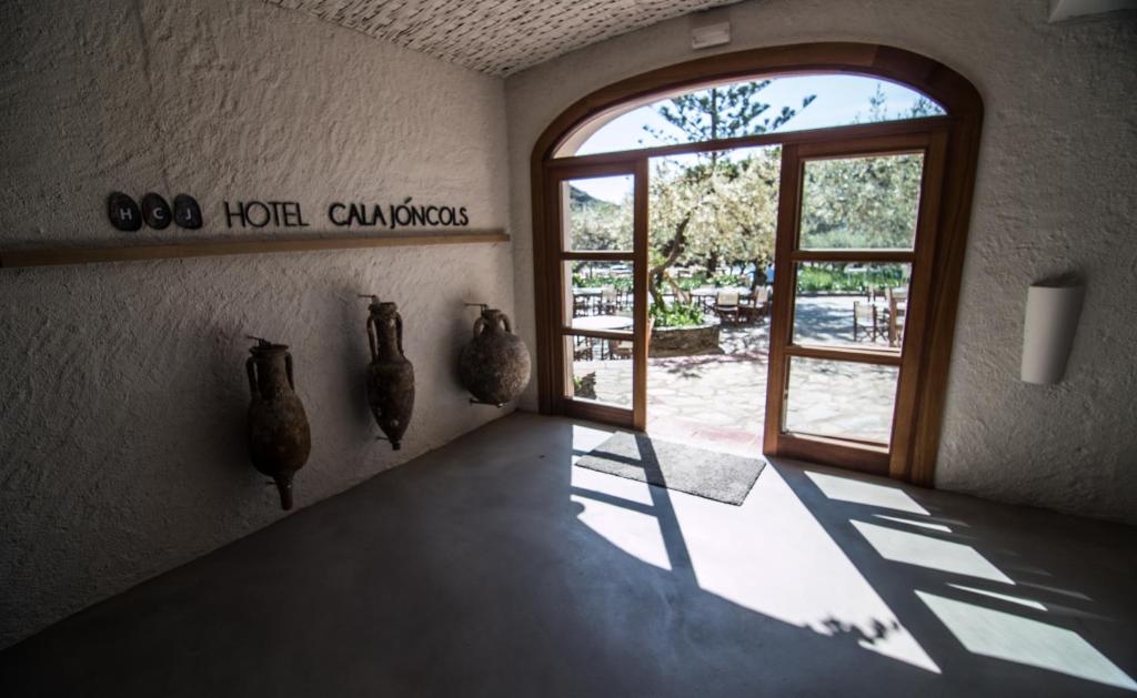 Habitación con puerta abierta con jarrones en la pared en Hotel Cala Joncols, en Roses