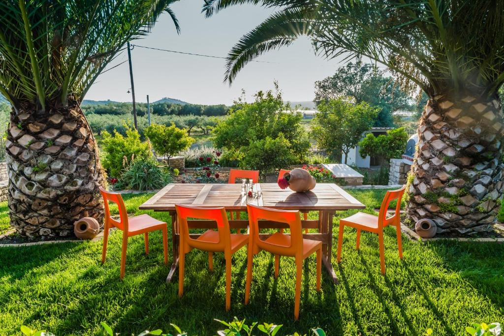 einen Holztisch und Stühle in einem Garten mit Palmen in der Unterkunft Aloni Home in Petrokefálion