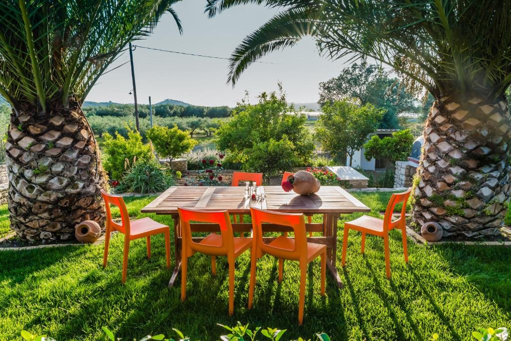 - une table et des chaises en bois dans une cour agrémentée de palmiers dans l'établissement Aloni Home, à Petrokefálion
