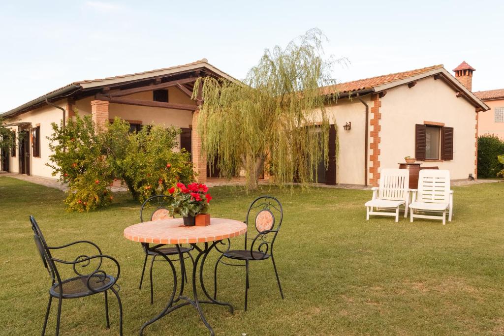 - une table et des chaises dans la cour d'une maison dans l'établissement Agriturismo Il Rustico, à Marina di Grosseto