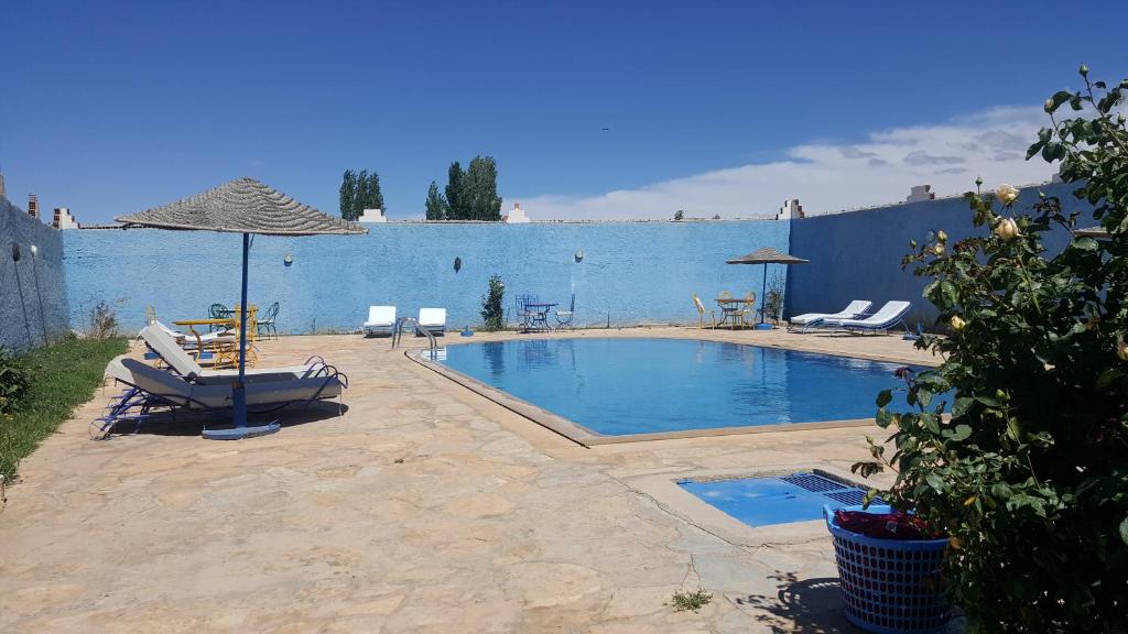 a swimming pool with two lounge chairs and an umbrella at Riad Villa Midelt in Midelt