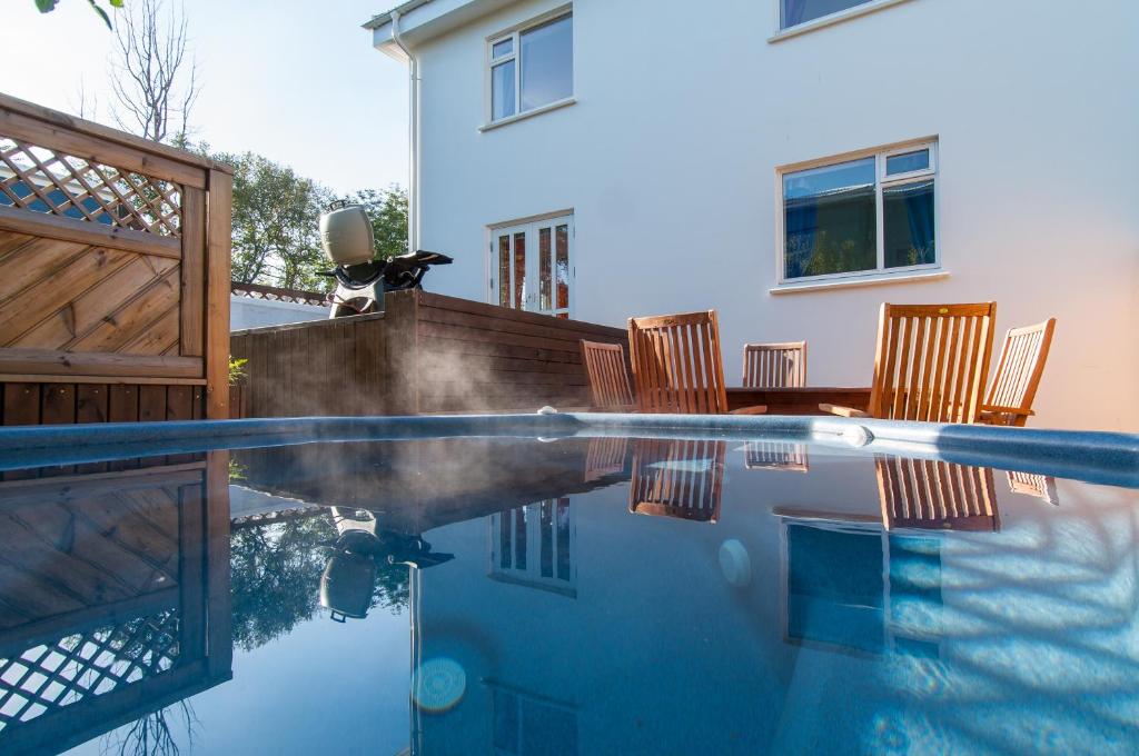 a swimming pool with chairs and a house at Pearl of the North Apartments in Akureyri