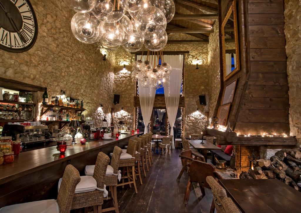 a restaurant with a bar with chairs and a chandelier at Teresa Country Lodge in Eptalofos