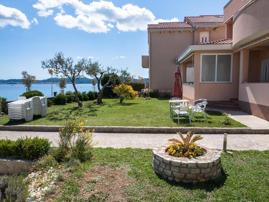 a house with a yard with a table and chairs at Apartments Nino 1 in Zadar