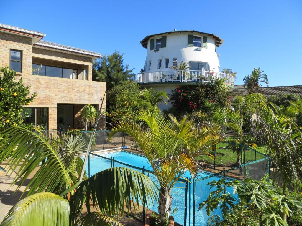 una casa y una piscina con un faro en el fondo en Cape Oasis Guesthouse, en Bloubergstrand