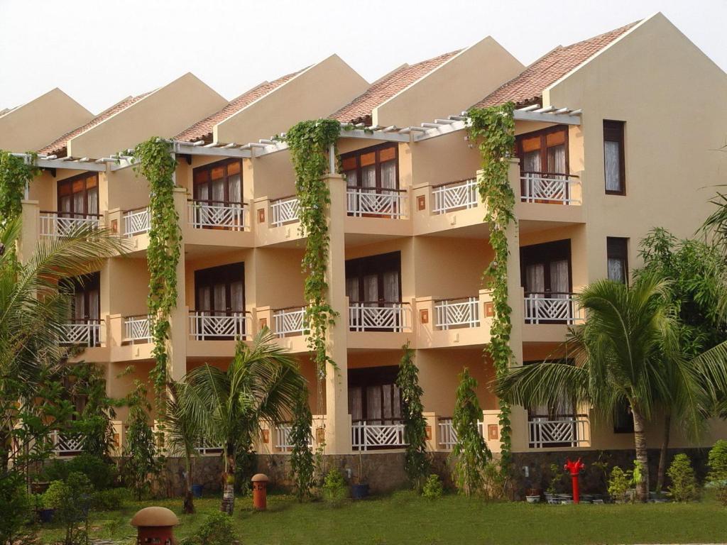 an apartment building with trees in front of it at Can Gio Resort in Cần Giờ