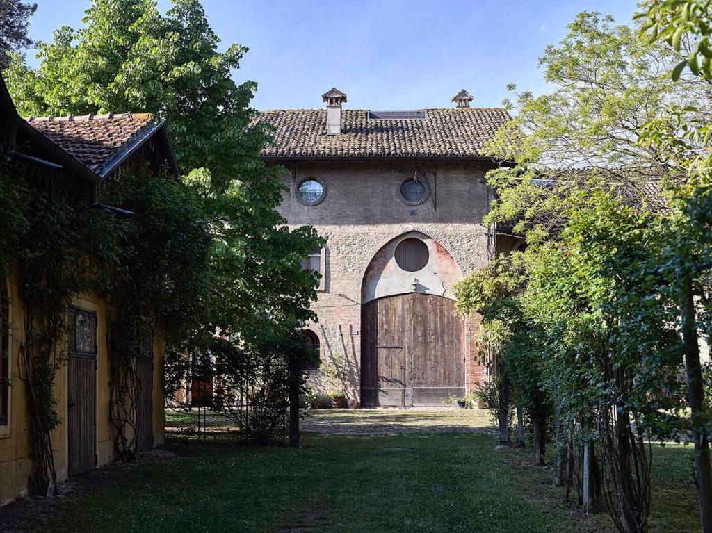 a building with an archway and a building with trees at Le dimore de Il borgo del balsamico in Albinea