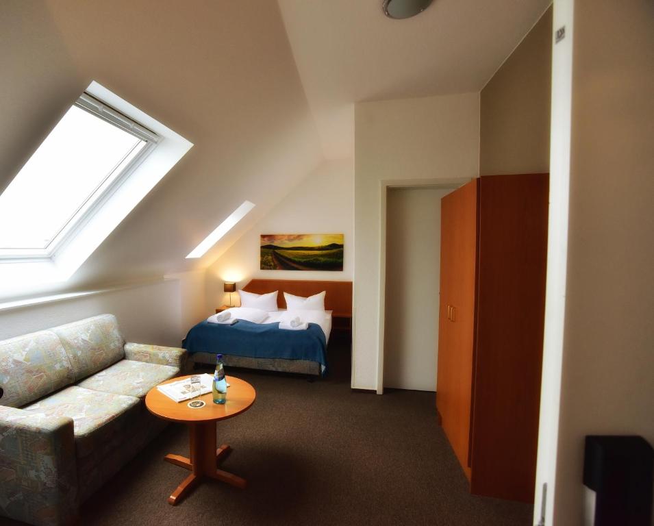 Cette chambre dispose d'un canapé, d'un lit et d'une fenêtre. dans l'établissement Goethe Hotel Messe by Trip Inn, à Francfort-sur-le-Main