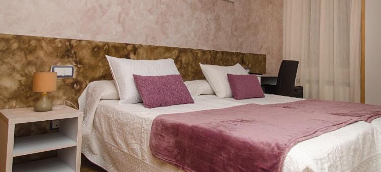 1 dormitorio con 1 cama grande con almohadas moradas y blancas en Hostal Don Rodrigo, en Zamora