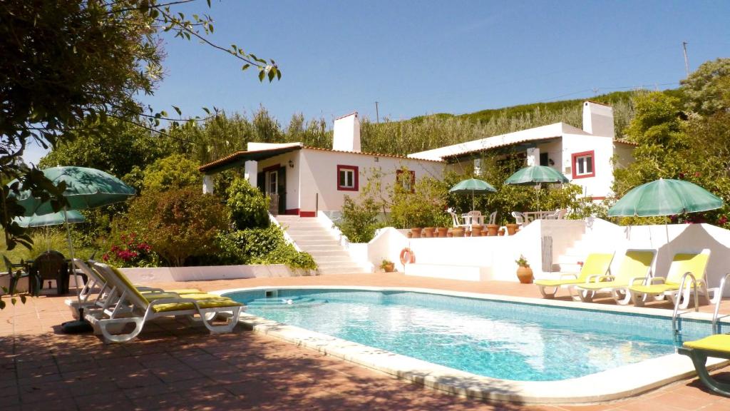 a villa with a swimming pool in front of a house at Casa dos Mangues in São Martinho do Porto