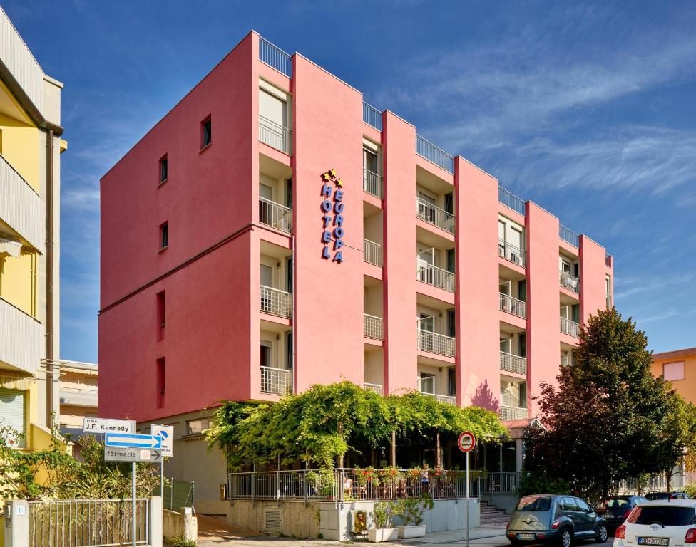 un edificio rosa con un cartello sul lato di Hotel Europa a Grado