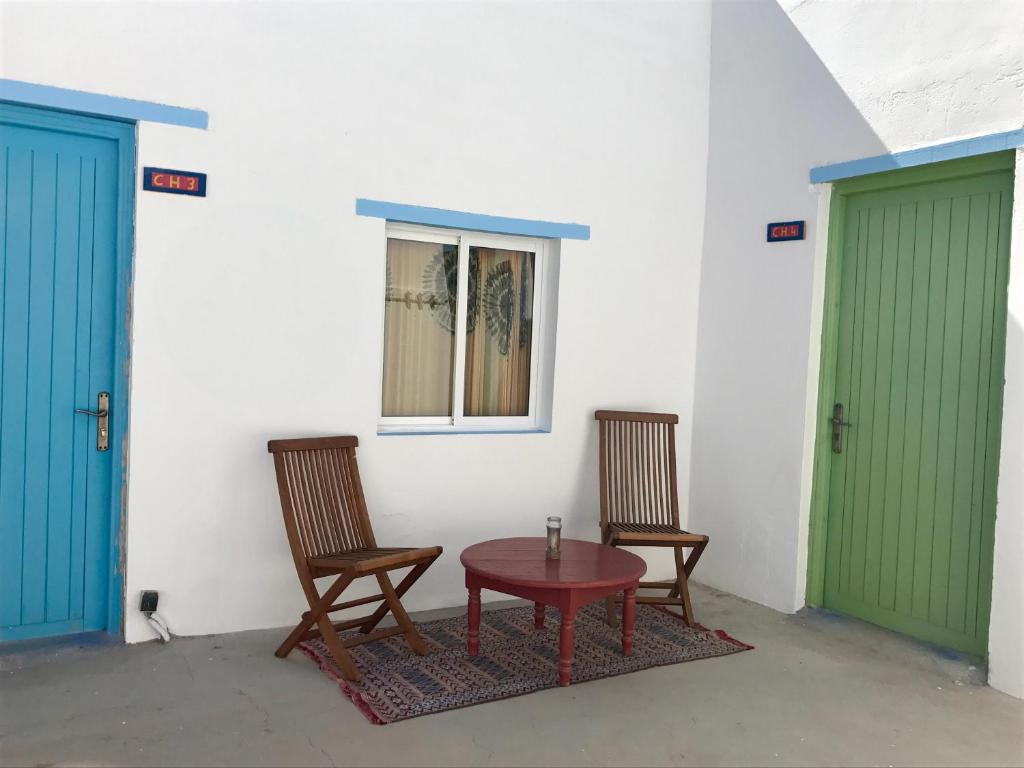 two chairs and a table in a room with two doors at Gite Le Nomade in Mirleft