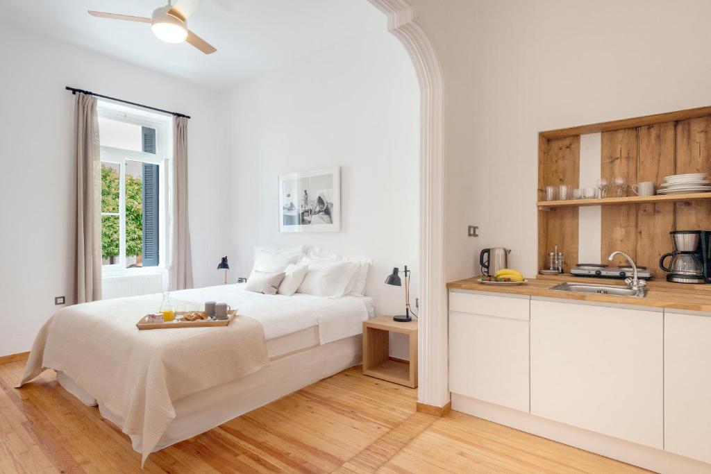 a white bedroom with a bed and a kitchen at Athens Residence Apartments in Athens