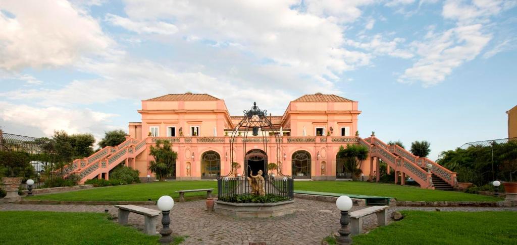 ein großes rosafarbenes Gebäude mit einem Brunnen davor in der Unterkunft Villa Signorini Hotel in Ercolano