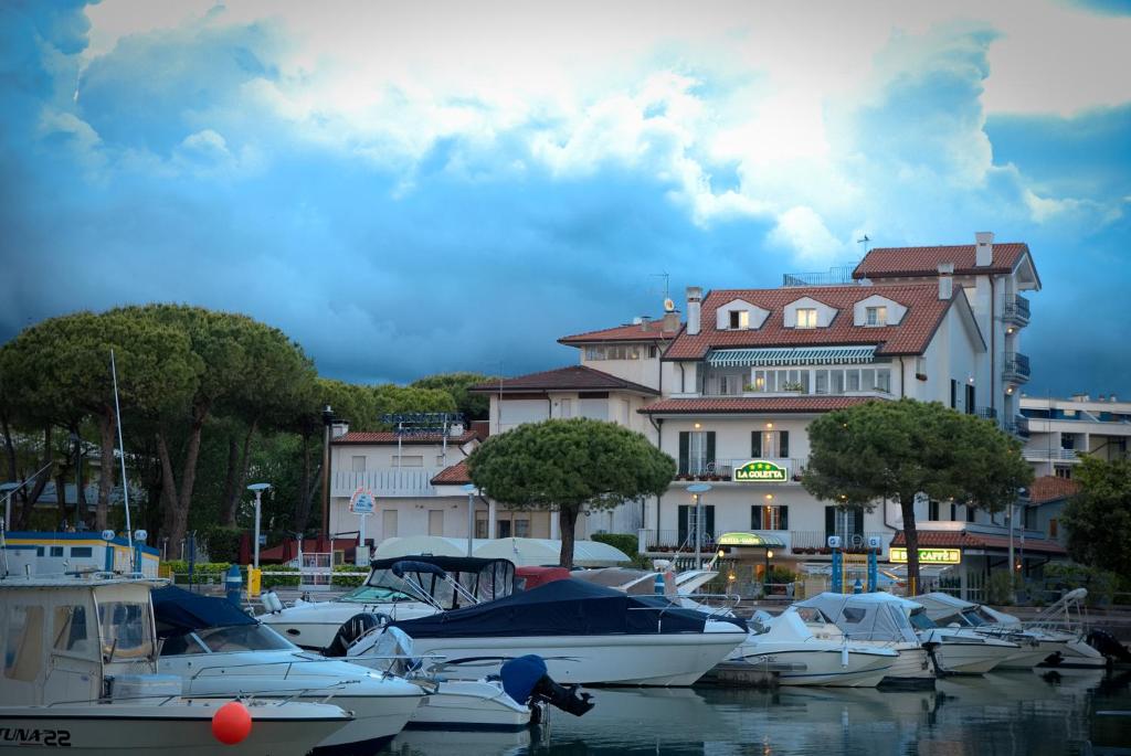 un grupo de barcos atracados en un puerto con un edificio en Hotel La Goletta, en Lignano Sabbiadoro