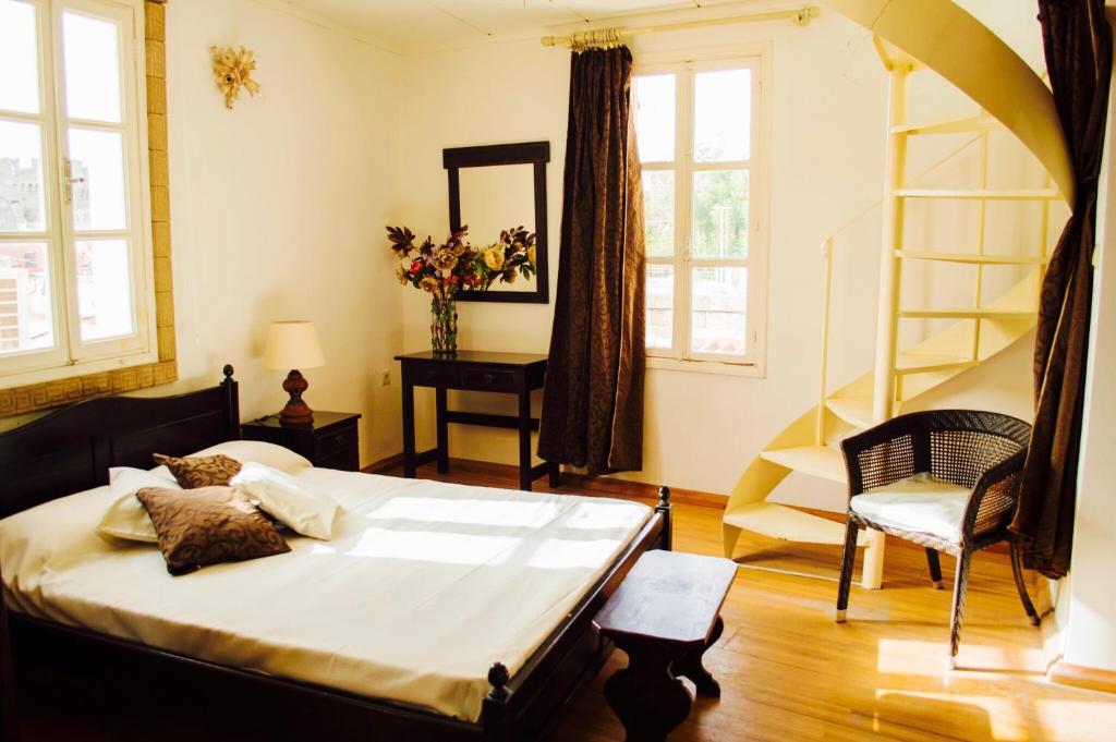 a bedroom with a bed and a chair and windows at Casa Kastellania in Rhodes Town