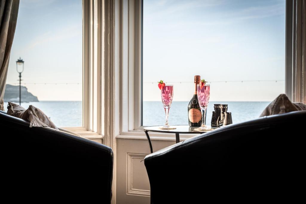 a table with two wine glasses and a window at The Grafton Guest House in Llandudno