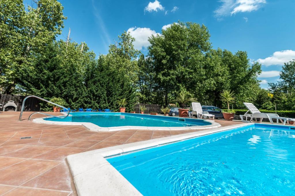 a swimming pool in a resort with chairs and trees at Pater Apartments and Rooms in Siófok