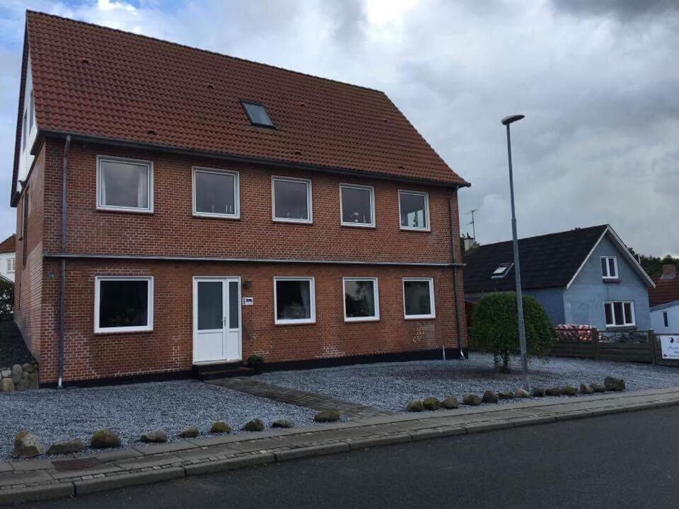 a brick house with white doors on a street at Thy Ferielejlighed in Thisted