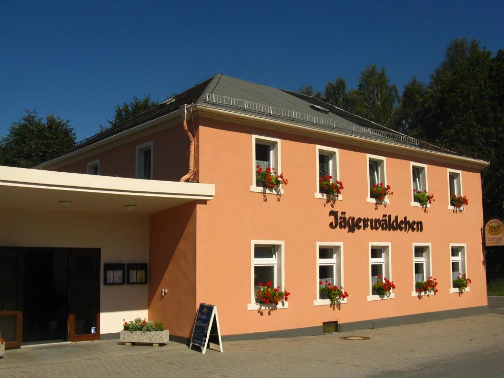 un bâtiment avec des boîtes de fleurs sur son côté dans l'établissement Gaststätte & Pension Jägerwäldchen, à Bertsdorf