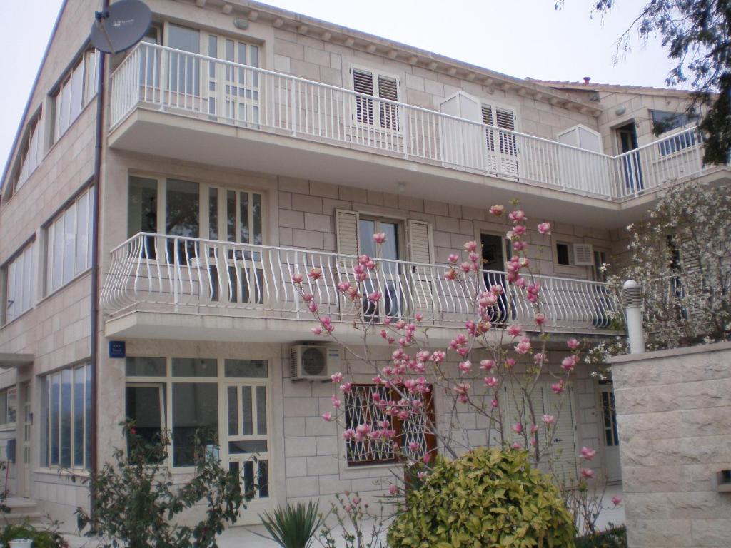 un edificio de apartamentos con balcón y flores rosas en Villa Magnolija, en Mlini