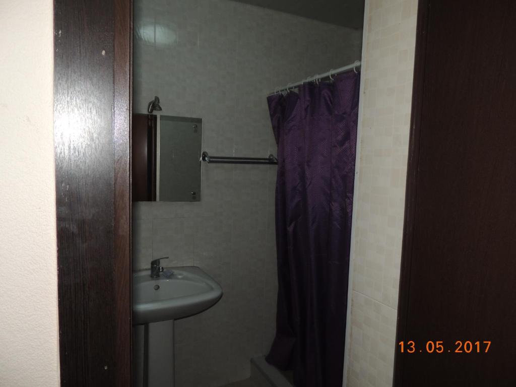a bathroom with a sink and a purple shower curtain at Galavnis Kari Hotel in Sighnaghi