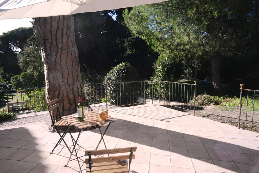 einen Tisch und einen Stuhl unter einem Regenschirm neben einem Baum in der Unterkunft Grand Balaguier in La Seyne-sur-Mer