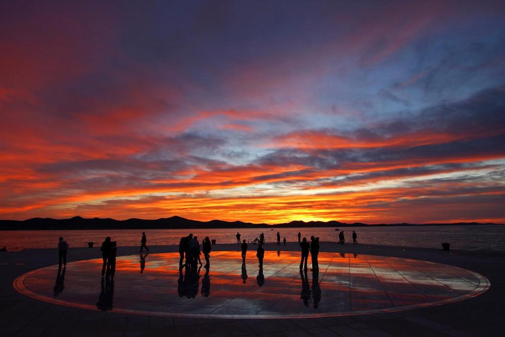 un groupe de personnes debout devant un coucher de soleil dans l'établissement Apartment Angela, à Zadar