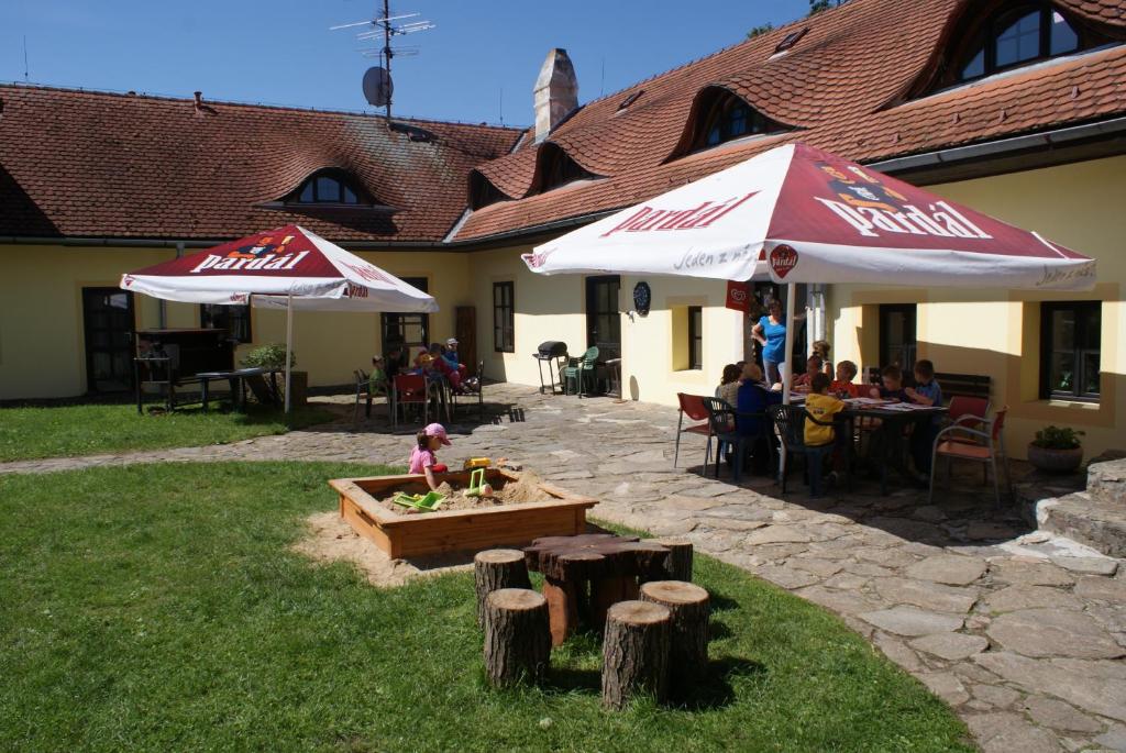 a patio with people sitting at tables and umbrellas at Penzion Pístina in Stráž nad Nežárkou