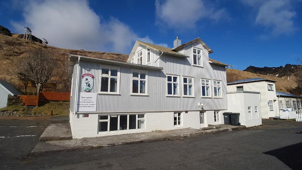 a white building with a banner on the side of it at Puffin Hostel Vík in Vík